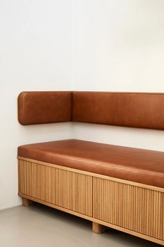 a brown leather bench sitting on top of a wooden shelf next to a white wall