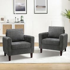 two gray chairs sitting next to each other on a rug in front of a white wall