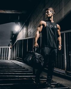 a man holding a duffel bag while standing on stairs