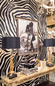 a zebra print wall with two lamps and a painting on it's side table