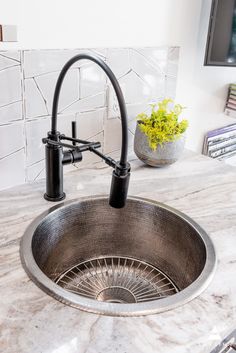 a sink that has a faucet on top of it and a potted plant in the corner