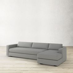 a gray couch sitting on top of a wooden floor next to a white wall with a plant