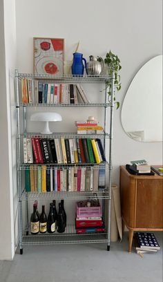 a book shelf filled with lots of books next to a red chair and table lamp