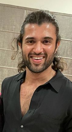 a man with long hair smiling at the camera