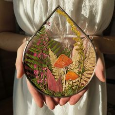 a person holding a glass plate with flowers and plants