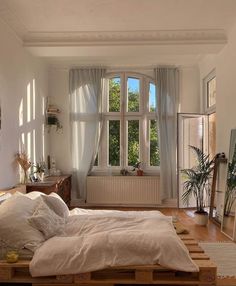 a bed sitting in a bedroom next to a window filled with lots of windows and plants