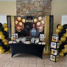 a table with balloons and pictures on it in front of a stone fireplace at a graduation party