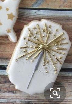 two decorated cookies sitting on top of a wooden table next to each other with gold stars