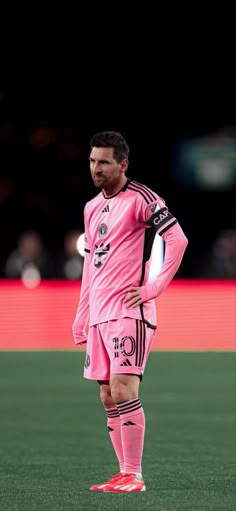 a man standing on top of a soccer field wearing a pink uniform and red shoes