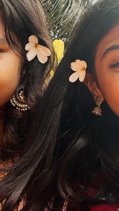 two girls with flower clips on their hair posing for the camera, one girl is smiling at the camera