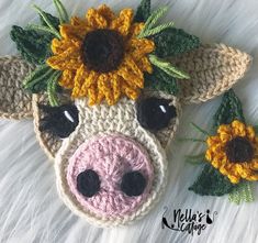 a crocheted cow with sunflowers on it's head is laying down