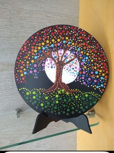 a colorful tree painted on the side of a wooden wall hanging from a hookseat