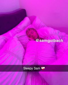 a person sleeping in a bed with pink sheets