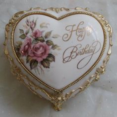 a white and gold heart shaped box with roses on it's sides that says happy birthday