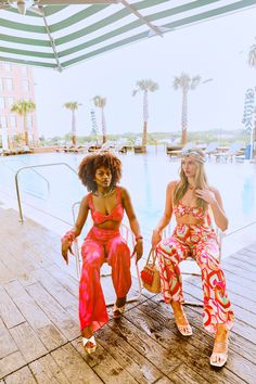 two women sitting next to each other near a swimming pool