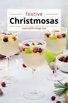 two glasses filled with white wine and topped with cranberries on a table next to christmas decorations