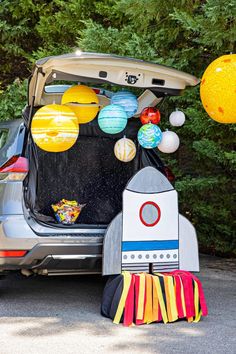 an open back car trunk filled with space themed items and balloons in the shape of planets