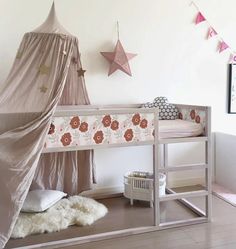 a white bunk bed with a pink canopy and stars on the wall next to it