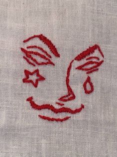 embroidered face on white linen with red thread