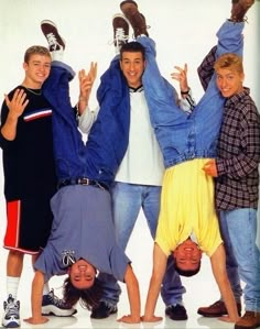 four young men are standing in front of each other with their hands up and one is upside down