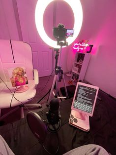 a pink room with a camera, laptop and chair in front of the light that is turned on