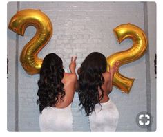 two women standing in front of gold balloons with the number 22 on it's side