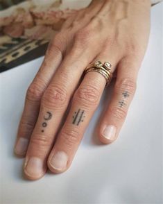 a woman's hand with tattoos on it and a ring in the middle of her finger