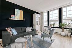 a living room filled with furniture and lots of window sill space next to a painting on the wall