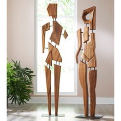 two wooden mannequins standing next to each other in front of a window