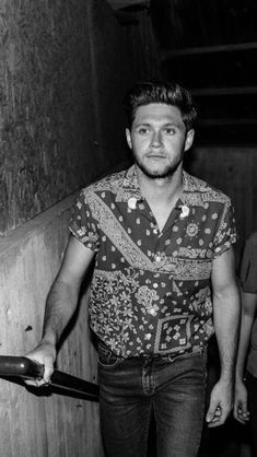 a black and white photo of a man holding a skateboard in his right hand