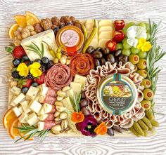 an assortment of cheeses, fruits and nuts arranged on a platter with flowers