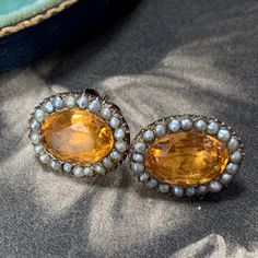 Georgian topaz and split pearl earrings in a closed back gold setting. A stunning pair of earrings beset with a split natural pearl halo that surrounds a majestic oval cut topaz. In outstanding condition, circa 1800 - 1820 and historically converted to post and butterfly fittings for easy and everyday use. Very rare indeed especially in this amazing condition. A very splendid and truly mesmerizing antique treasure to grace your ears. In historical contexts, topaz was considered a protective ston Victorian Baroque Earrings For Formal Occasions, Victorian Baroque Earrings, Victorian Yellow Gold Clip-on Earrings, Victorian Style Yellow Gold Clip-on Earrings, Victorian Pearl Earrings For Anniversary, Antique Drop Pearl Earrings For Formal Occasions, Antique Pearl Drop Earrings For Formal Occasions, Victorian Style Pearl Earrings For Evening, Victorian Screw Back Wedding Earrings