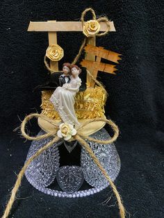 a glass vase with some sort of decoration on it's top and two people sitting on the base