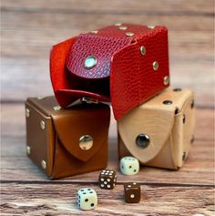 three leather dice holders with one open and the other closed, sitting on a wooden surface