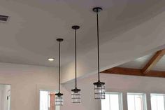 three light fixtures hanging from the ceiling in a room with white walls and wood beams