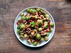 a white plate topped with brussel sprouts and pomegranate