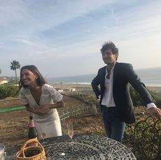 a man and woman standing next to an outdoor table