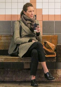 a woman sitting on a bench holding a cup