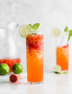 two glasses filled with drinks and garnished with limes