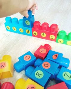 a child's hand is playing with letters and blocks