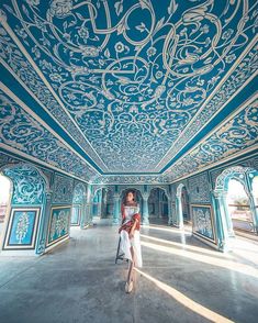 a woman sitting on the ground in an ornately decorated room with blue and white walls