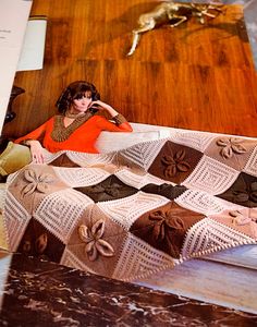 a woman sitting on the floor next to a crocheted blanket with flowers and leaves