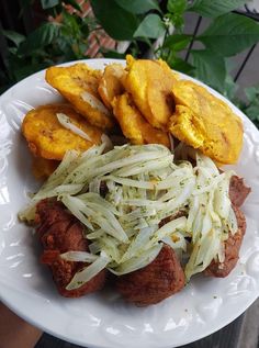 a white plate topped with meat and veggies next to potato wedges on top of a table