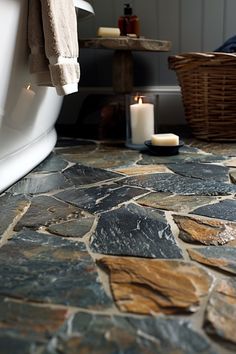 a bathroom with stone flooring next to a bathtub and towel on the rack