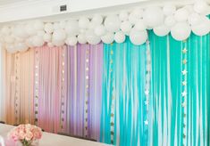 balloons and streamers are hanging from the ceiling in front of a table with flowers on it