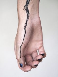 a woman's hand with a black tattoo on it and a blue nail polish