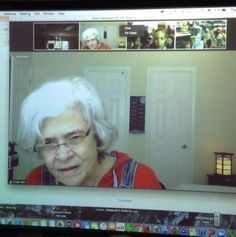 an old woman with glasses is on the computer screen and has white hair in front of her face