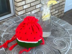 a knitted watermelon hat sitting on top of a table next to a vase