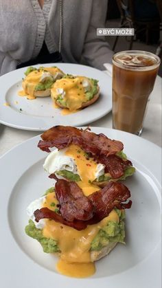 two plates with eggs, bacon and avocado on them next to a drink