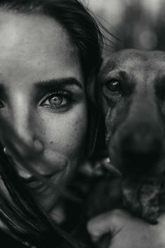 a black and white photo of a woman holding a dog's face to her chest